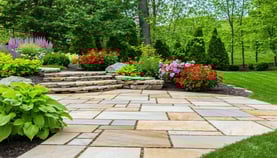 A beautifully landscaped yard with a stone patio,